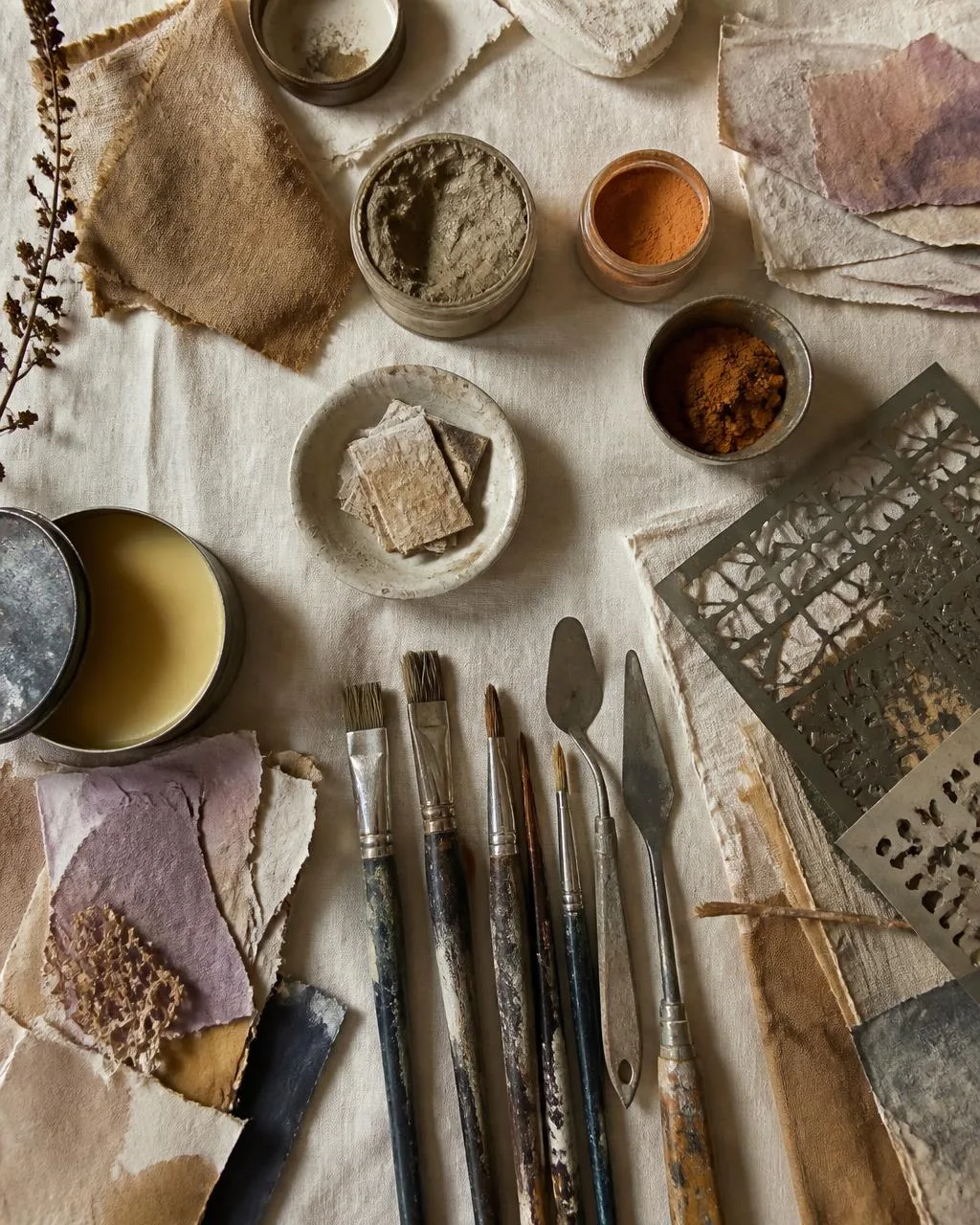 Studio table with brushes, pigment, and layered paper